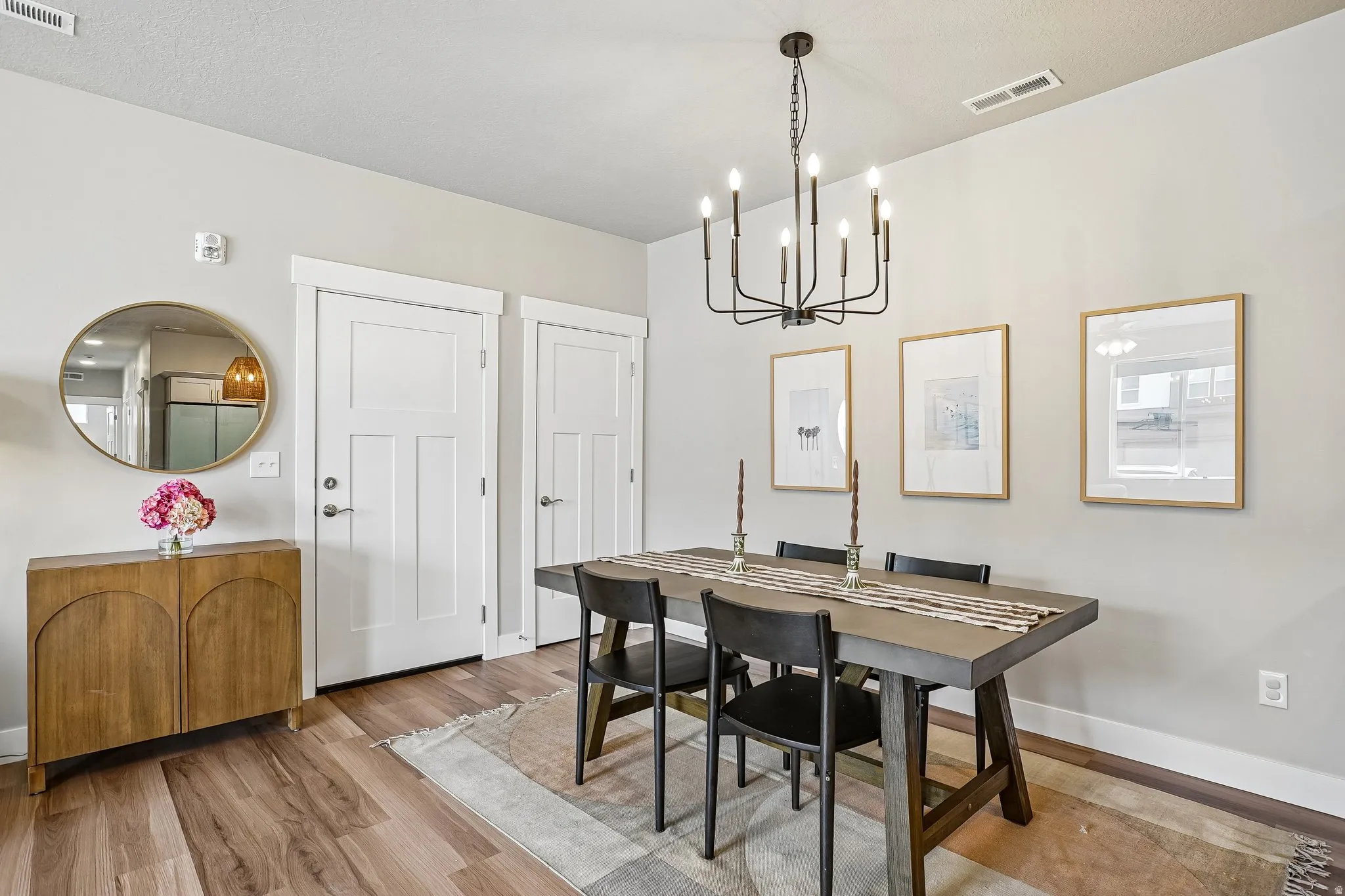 Dining area featuring wood-finish flooring, a modern black chandelier, white baseboards, and light-toned walls
