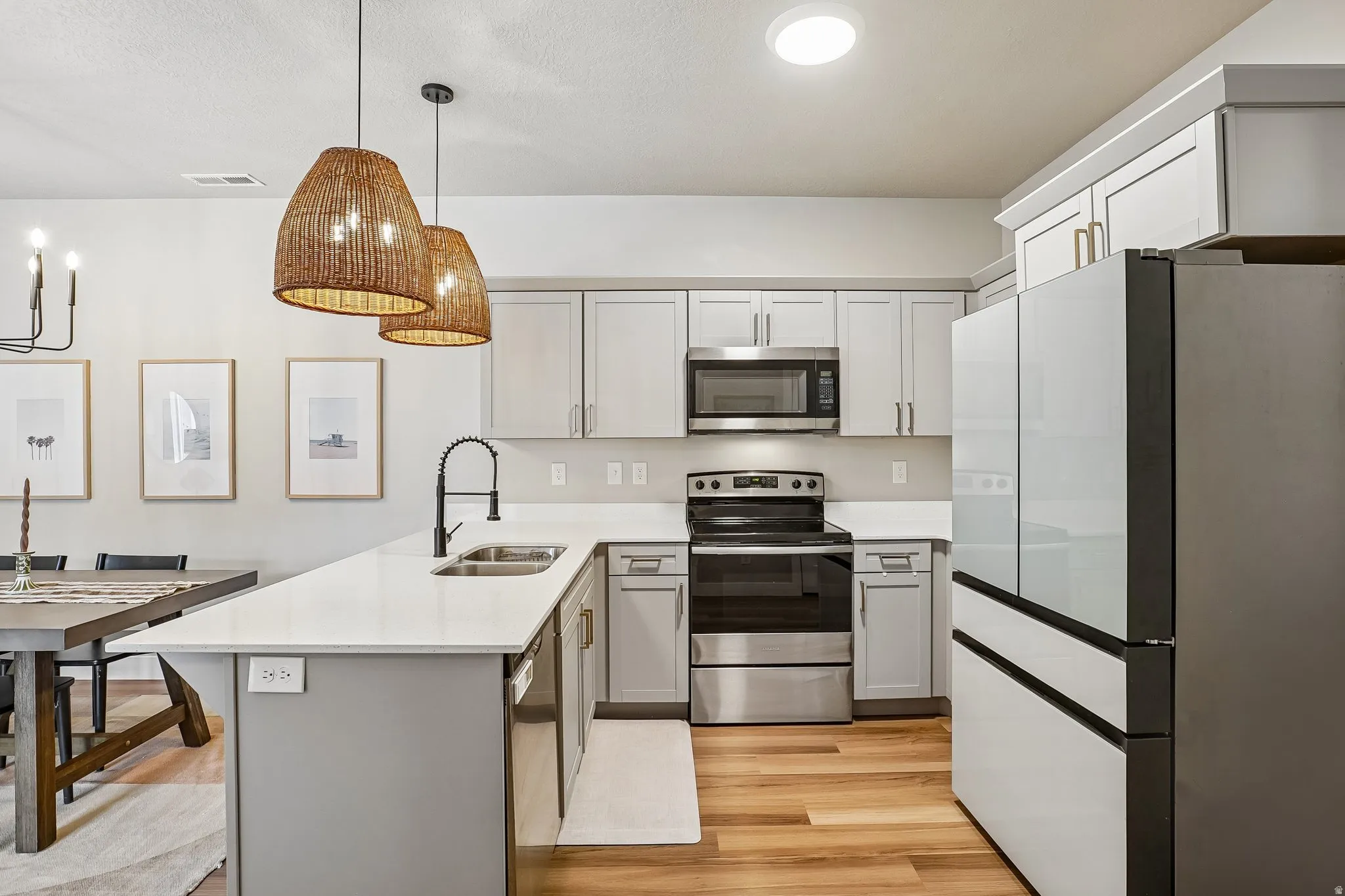 Modern kitchen featuring light gray cabinetry, white countertops, stainless steel appliances, and wood-finish flooring