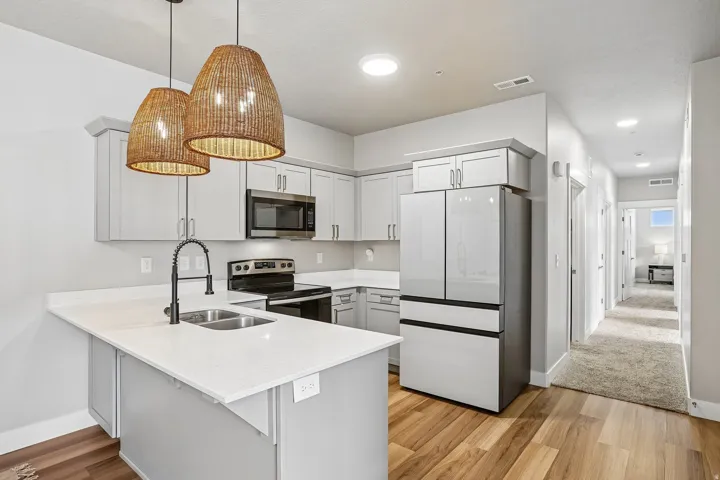 Modern kitchen featuring light gray cabinetry, stainless steel appliances, and a white countertop island with an undermount double sink
