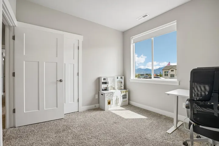 Window-filled room featuring neutral wall tones, plush carpet, and white trim