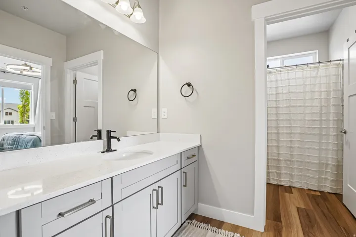 Bathroom vanity featuring a quartz countertop, undermount sink, and matte black faucet