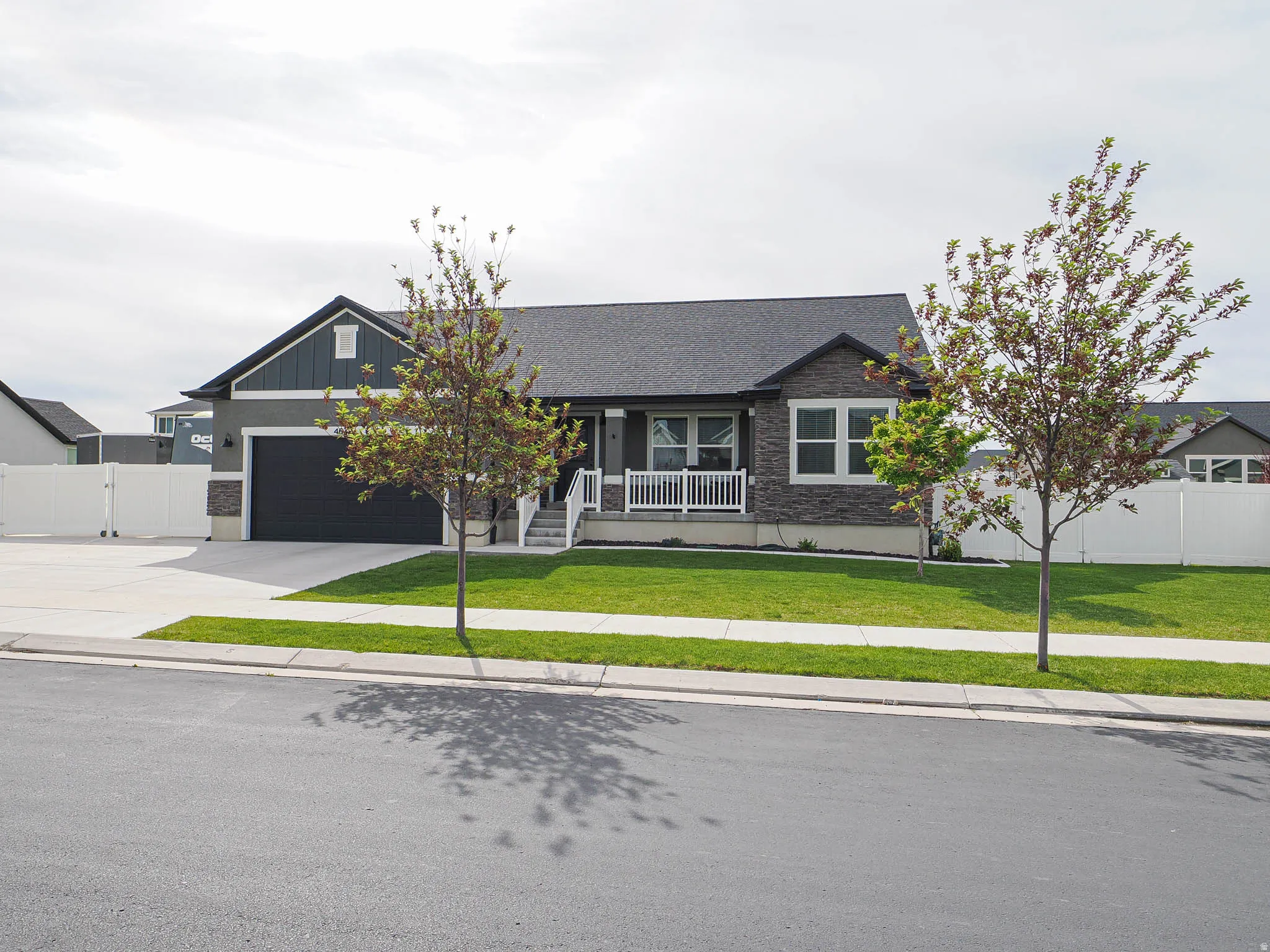 Ranch-style residence featuring a dark gray facade with stone accents and a covered front porch with white railings