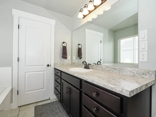 Bathroom vanity featuring a single basin sink, bronze-finish faucet, and a large mirror