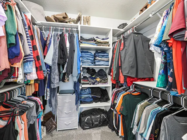 Walk-in closet featuring built-in shelving, multiple hanging rods, and carpet flooring