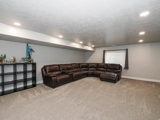 Spacious carpeted room featuring recessed lighting, a window with blinds, and light gray walls