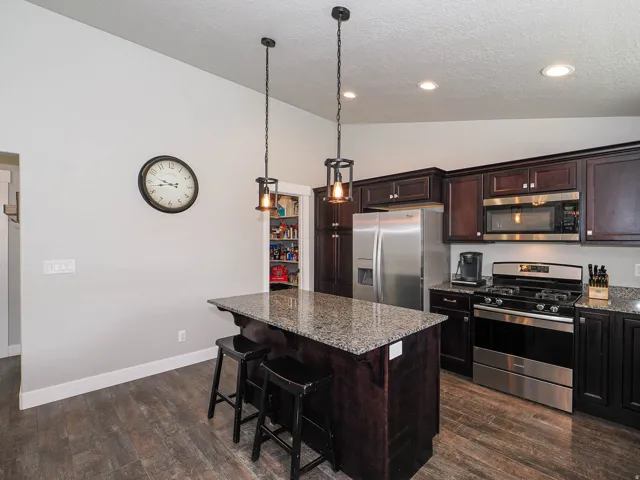 Kitchen featuring wood-finish flooring, dark wood cabinetry, and stainless steel appliances