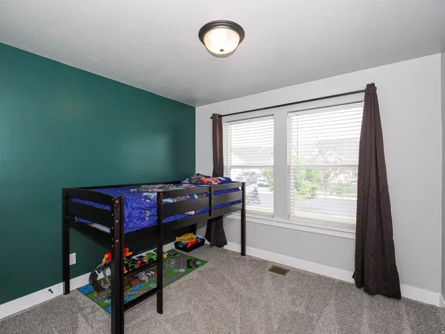 Room featuring light gray carpeting, a single accent wall in a deep green hue, and white baseboards