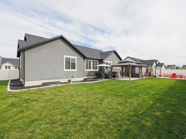 Expansive backyard featuring a manicured lawn, concrete patio, and a permanent gazebo structure