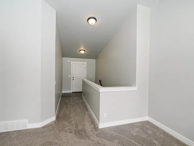 Carpeted hallway with light gray walls and white baseboards