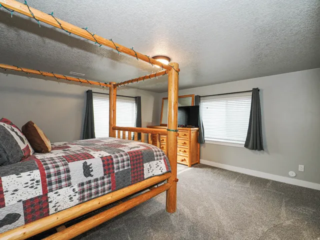 Carpeted room with light gray walls, two windows featuring white blinds and dark gray drapes, and a ceiling light fixture