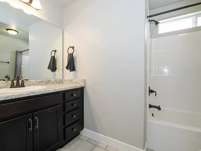 Bathroom featuring a dark wood-finish vanity with a light speckled countertop, an undermount sink, and oil-rubbed bronze fixtures