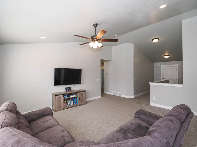 Spacious living area featuring neutral carpeting and light gray walls