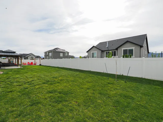 Expansive green lawn with a white privacy fence