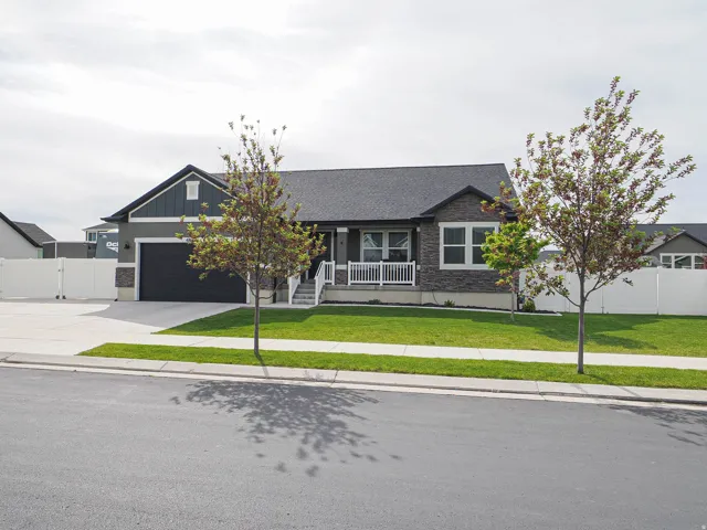Ranch-style residence featuring a dark gray facade with stone accents and a covered front porch with white railings