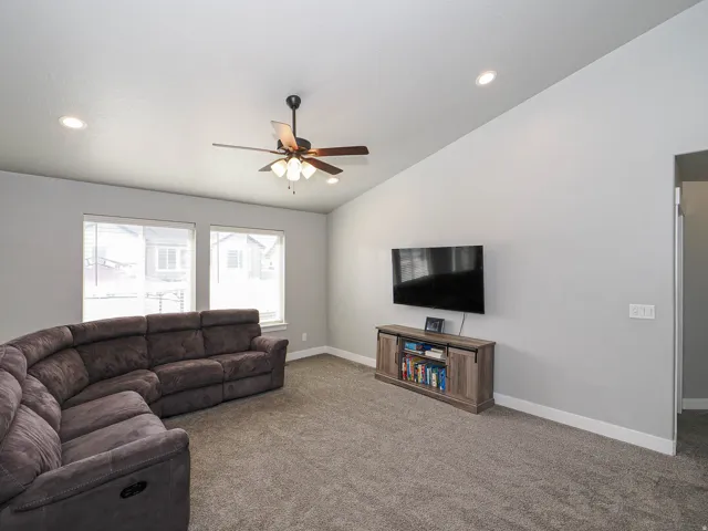 Vaulted ceiling with recessed lighting and a ceiling fan, featuring carpeted flooring and large windows