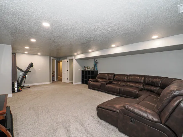 Spacious carpeted room featuring recessed lighting, light gray wall paint, white trim, and a white interior door