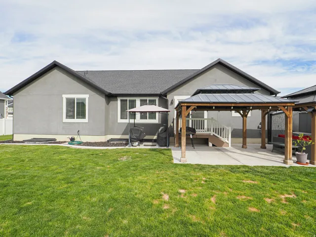 Expansive backyard featuring a lush lawn, concrete patio, and a wooden gazebo with a tiered roof