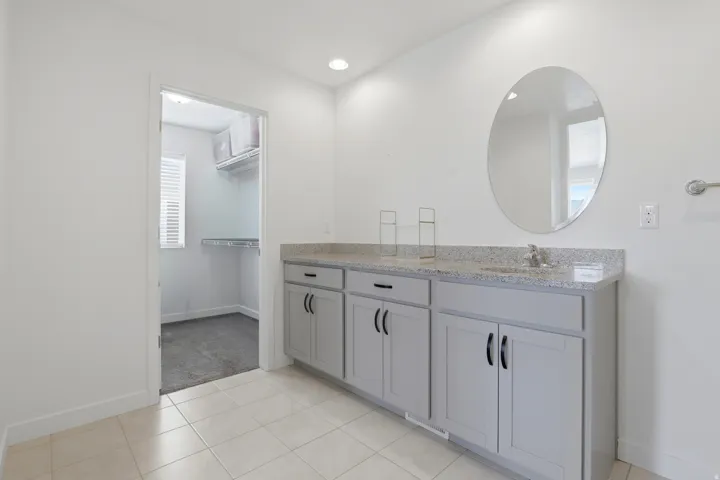 Vanity area featuring a light-toned countertop, dual sinks, and light gray cabinetry with black hardware