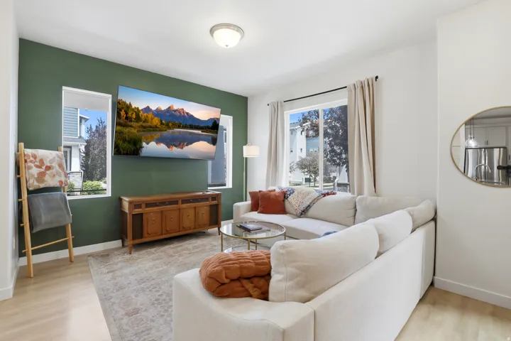 Living area featuring a prominent green  accent wall and light wood-finish flooring