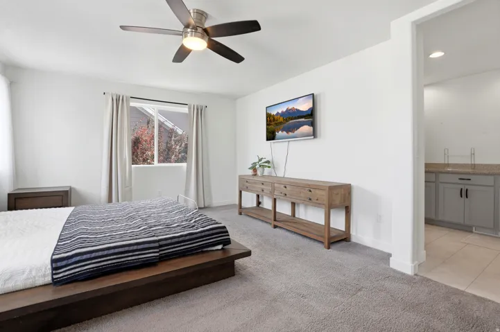 Spacious master bedroom featuring a ceiling fan with integrated lighting and full bathroom.