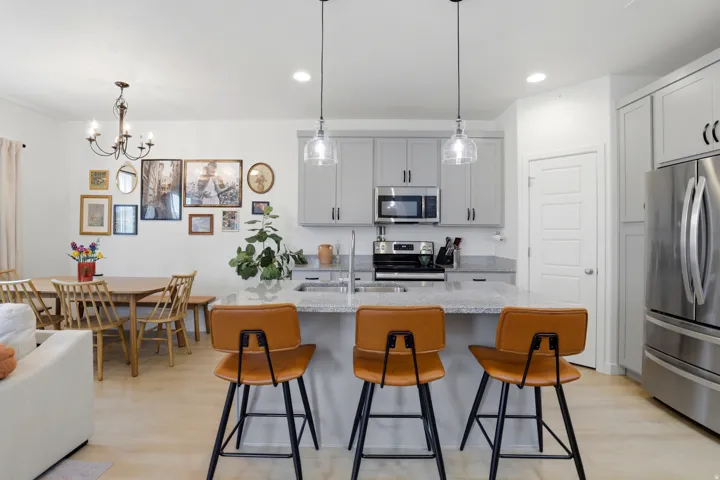 Open-concept kitchen perfect for entertaining, light gray cabinetry, stainless steel appliances,  a central island with a granite-finish countertop and pendant lighting and nice pantry for storage.