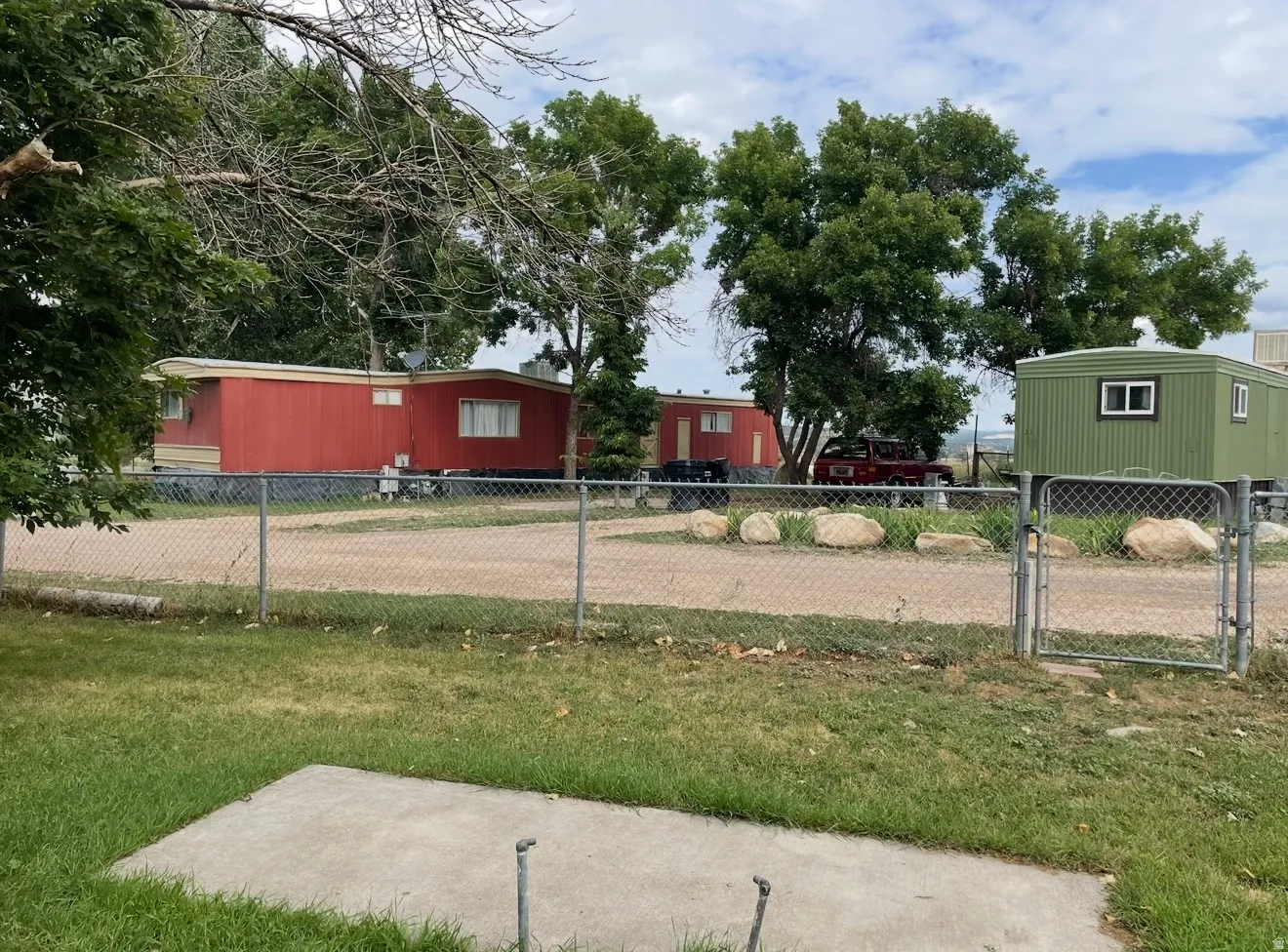 Fenced property featuring multiple structures, including two red-sided units and one green-sided unit