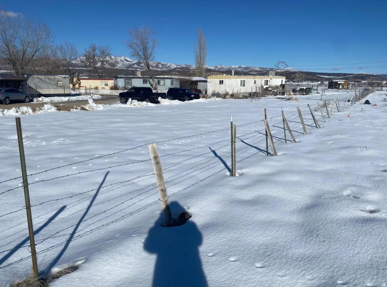 Expansive open field with barbed wire fencing and distant mountain ranges