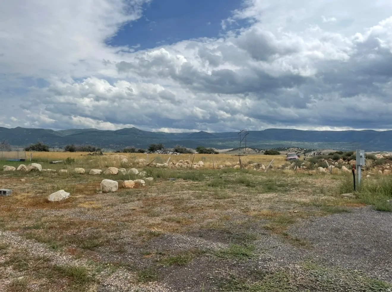 Expansive open land featuring distant mountain ranges and scattered rock formations