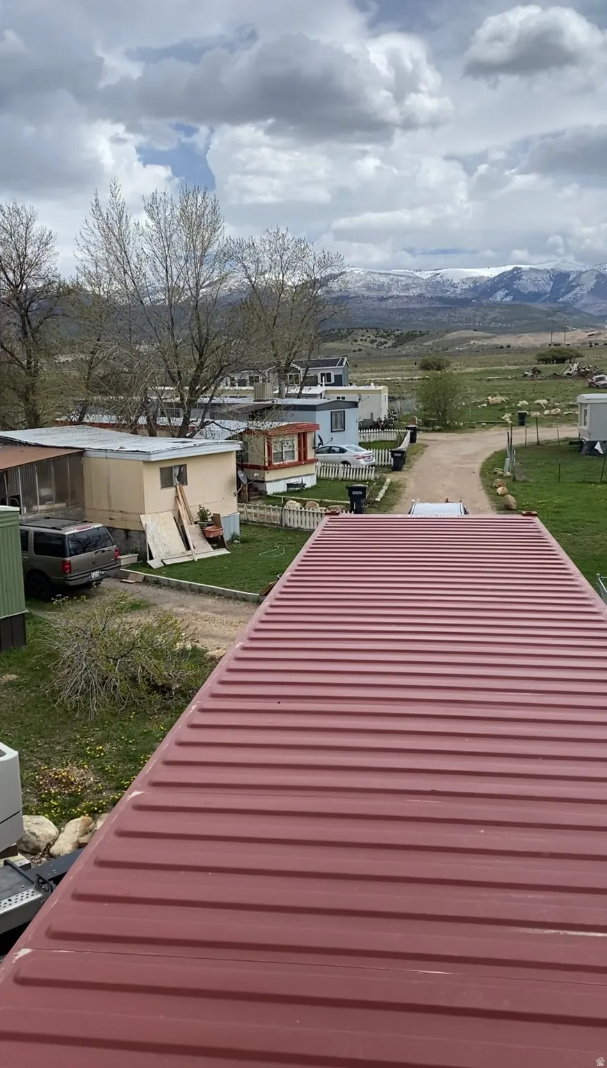 Corrugated metal roof with a distant mountain backdrop and visible landscaping