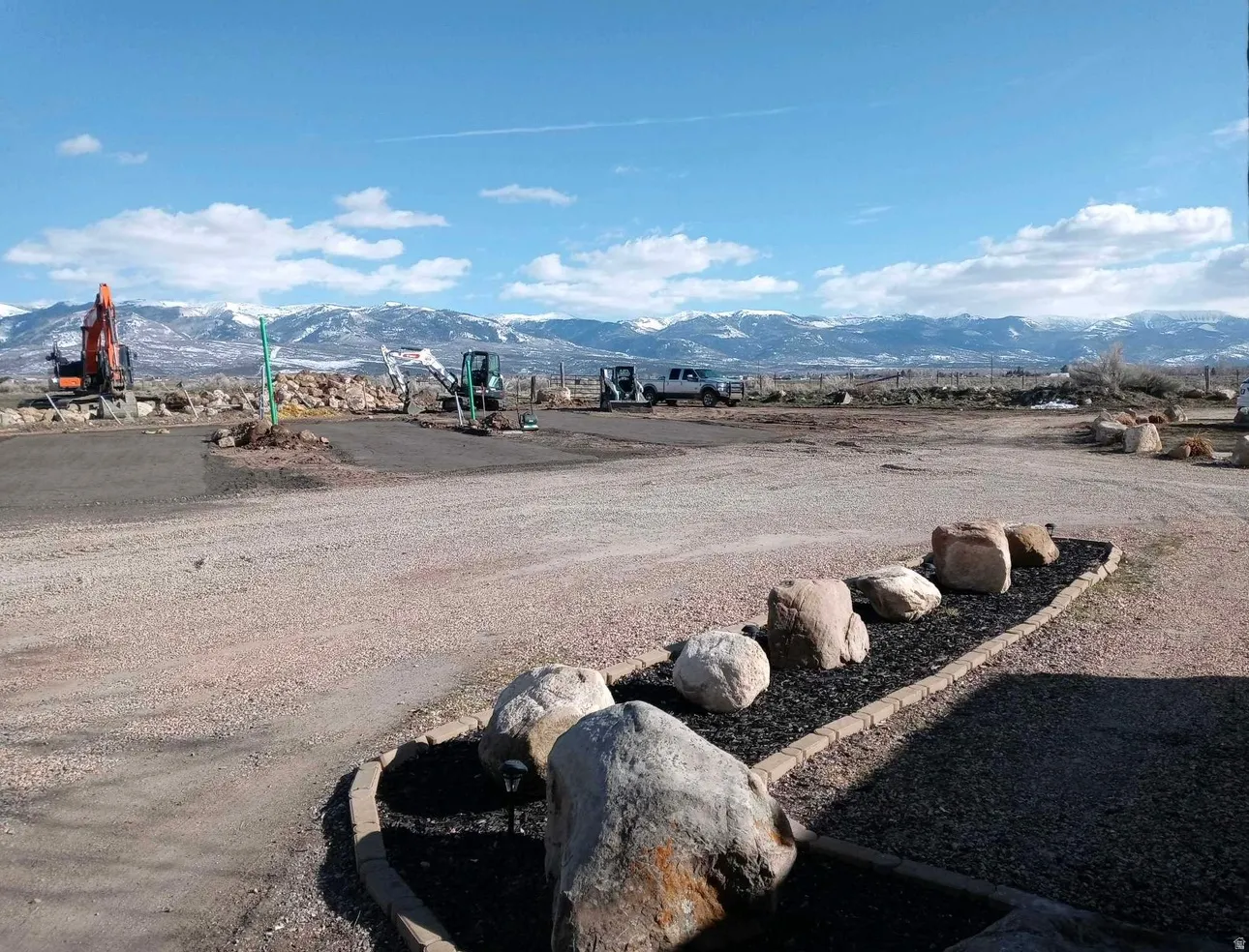 Expansive undeveloped lot with a gravel ground cover and a natural rock landscaping feature