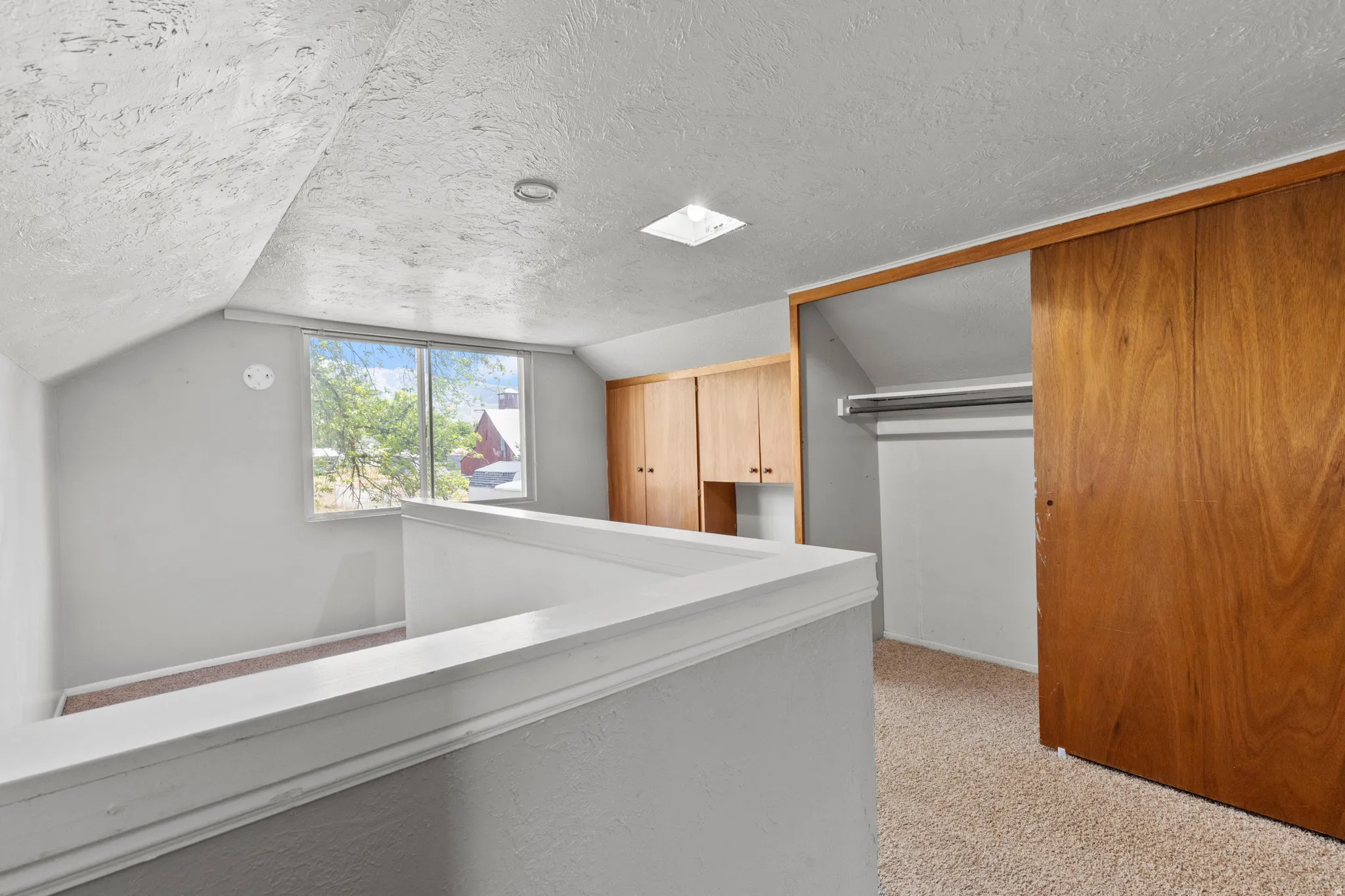 Loft area featuring a double window, built-in wooden cabinetry, carpeted flooring, and a sliding wooden closet door