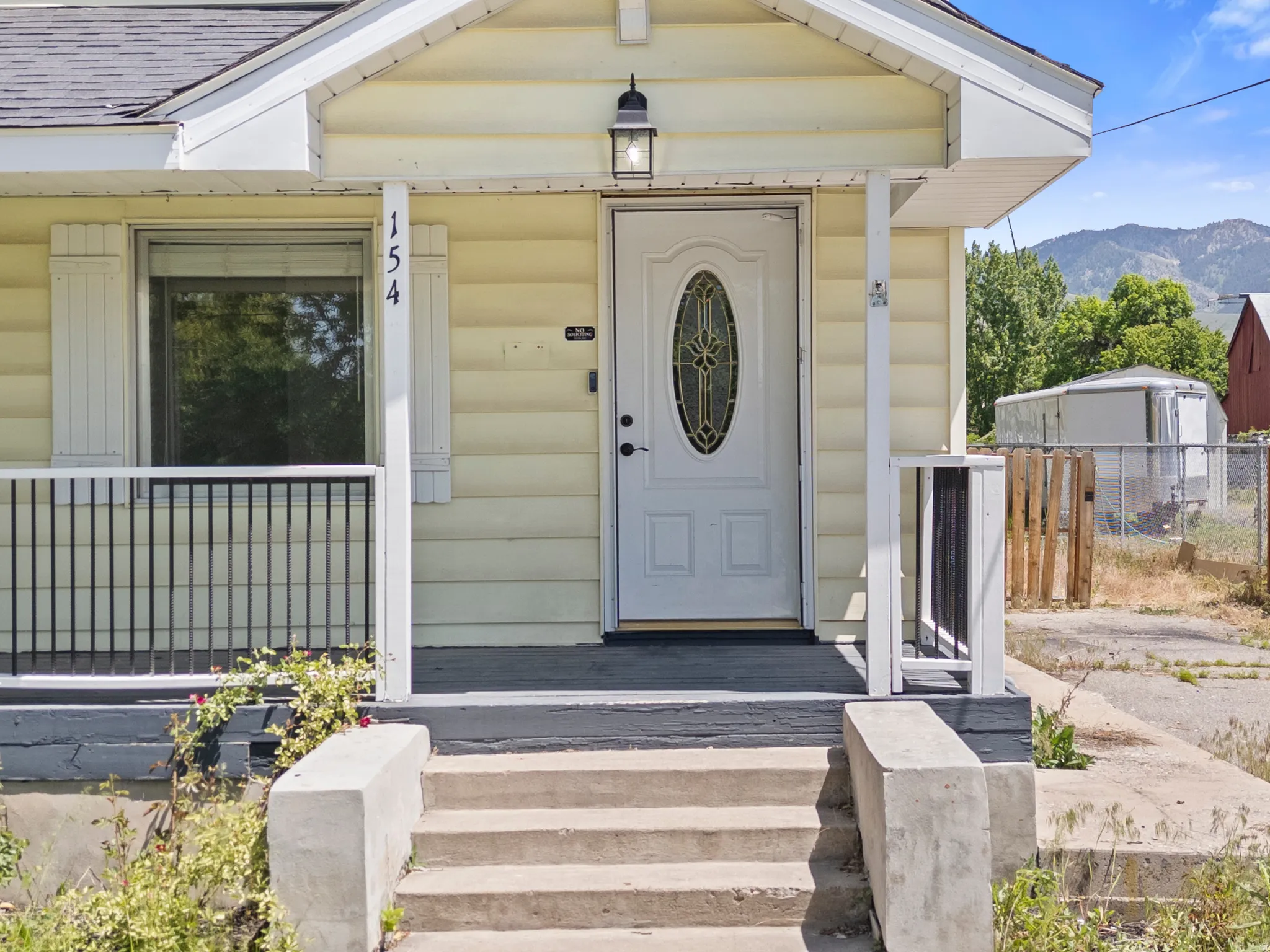 Front entry featuring a white oval-lite door with decorative glass, covered porch, and concrete steps
