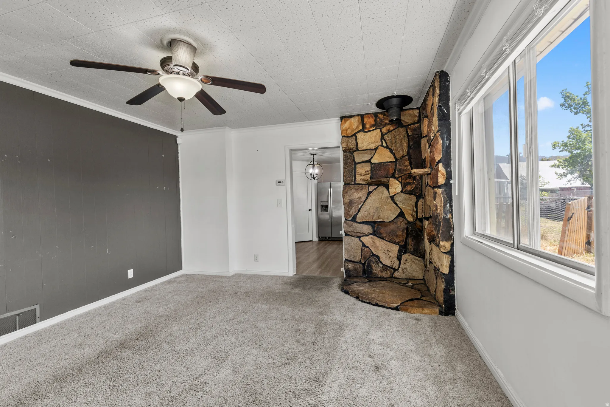 Living area featuring a stone accent wall that use to have a wood stove once removed, and ceiling light/fan combo.