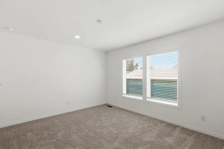 Carpeted interior space featuring dual windows with blinds, recessed lighting, white walls, and white baseboards