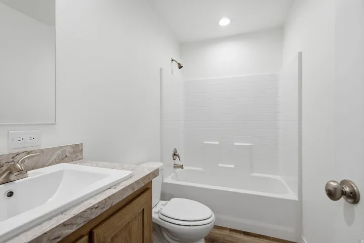 Bathroom featuring a wood-finish vanity with a single basin sink and a stone-look countertop