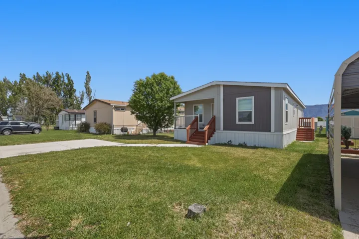 Manufactured home with two-tone siding, a front porch with wood-finish railing, and a side deck with wood-finish steps