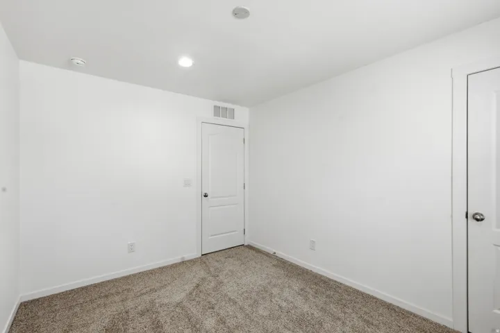 Neutral toned room featuring plush carpet flooring, white walls, and recessed lighting