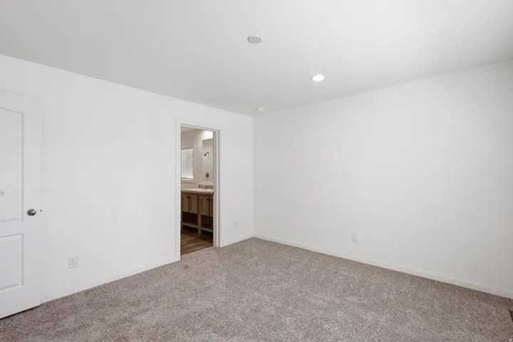 Carpeted room with recessed lighting and a white paneled door