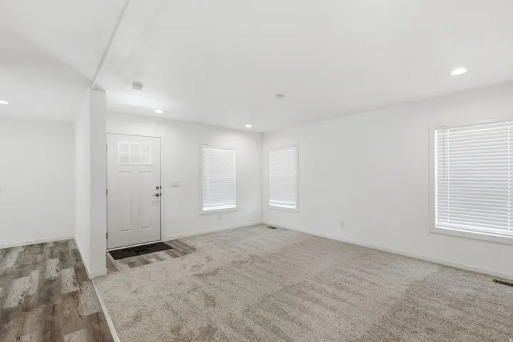 Entryway with a white paneled door featuring decorative glass inserts, complemented by recessed lighting and a wood-finish flooring