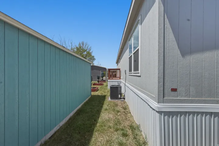 Side exterior featuring light gray vertical siding, white trim, and a white window frame