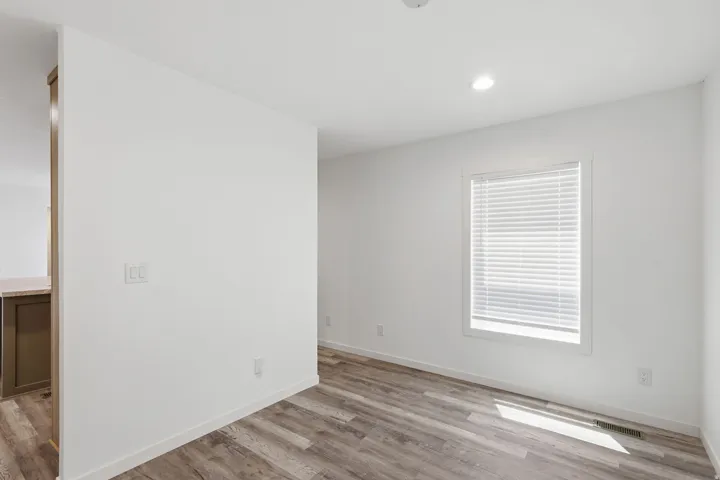 Bright interior space featuring wood-finish flooring, recessed lighting, and a window with horizontal blinds