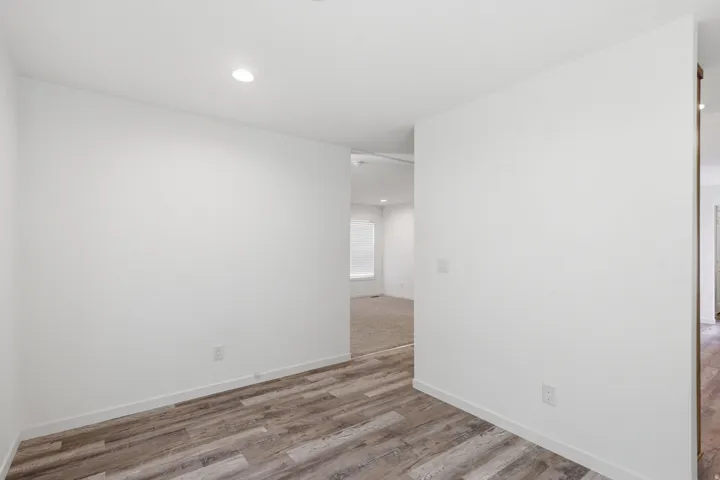 Interior space featuring wood-finish flooring, white walls, recessed ceiling lighting, and white baseboards
