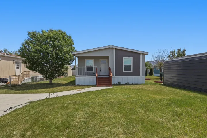 Single-story home featuring a covered front porch with white railings, brown exterior siding, and a concrete driveway