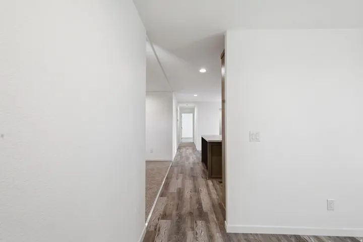 Hallway featuring wood-finish flooring, recessed lighting, and white walls