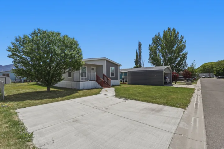 Single-story residence featuring a covered front porch with red-painted railings, a concrete driveway, and a detached carport