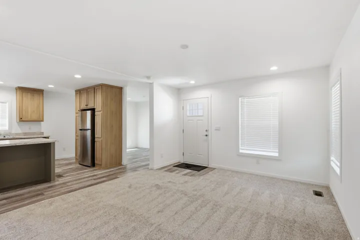 Open-concept living area featuring a neutral carpet and wood-finish flooring