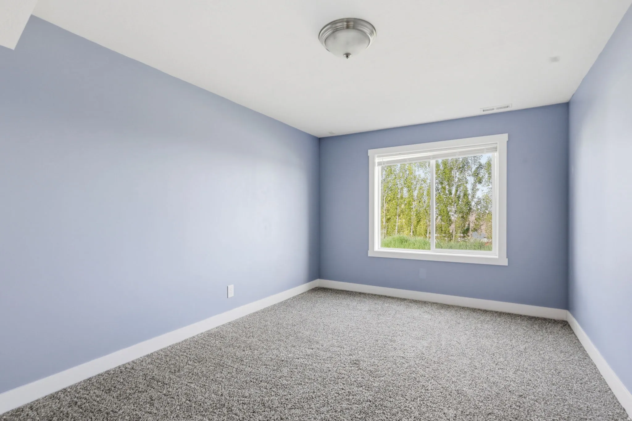 Room featuring a window with white trim, light blue walls, and gray carpet flooring