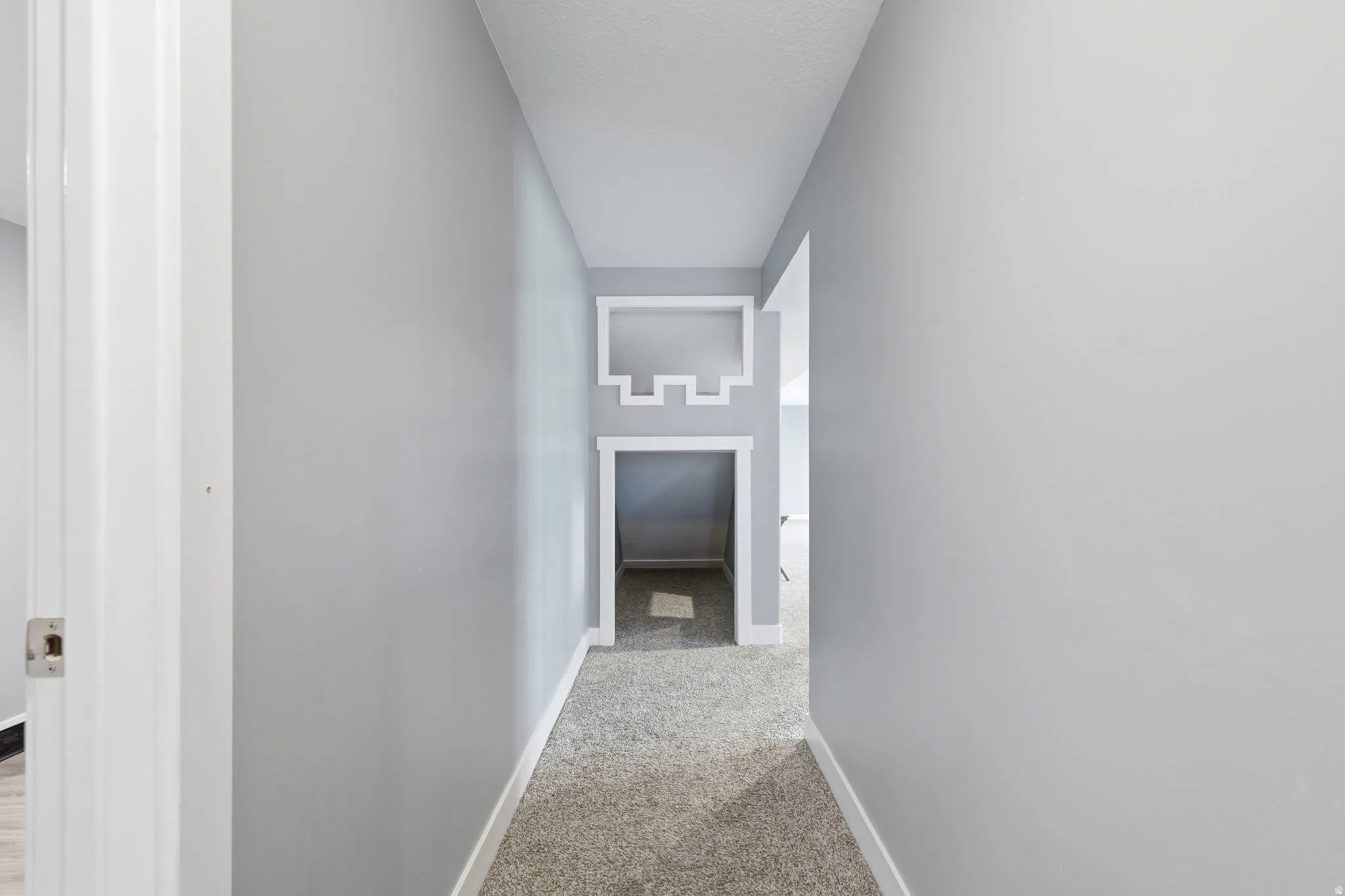 Hallway featuring light gray wall paint, white baseboards, and light-colored carpet flooring