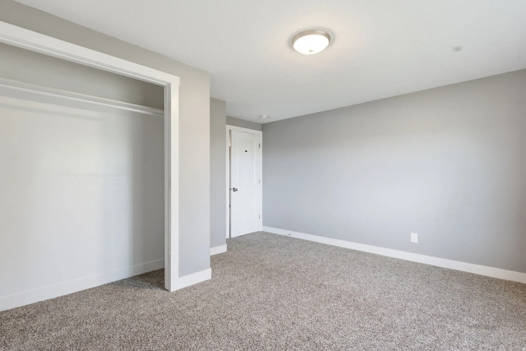 Spacious room with plush gray carpeting and neutral wall tones