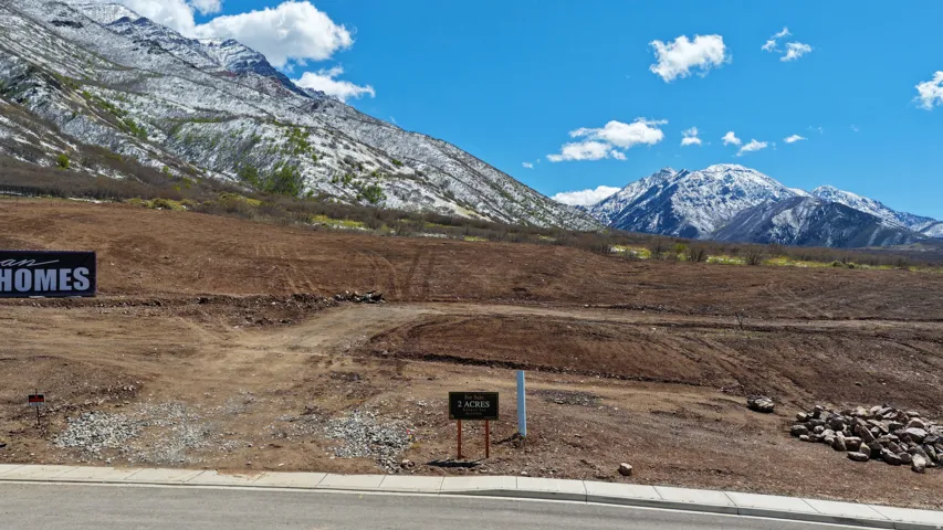 Expansive undeveloped lot featuring a mountainside setting, with a paved road frontage, and a distant mountain range